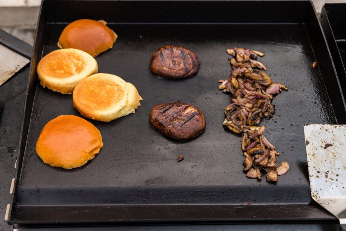 sliced mushrooms, burger buns, and portobello mushroom caps on grill grate
