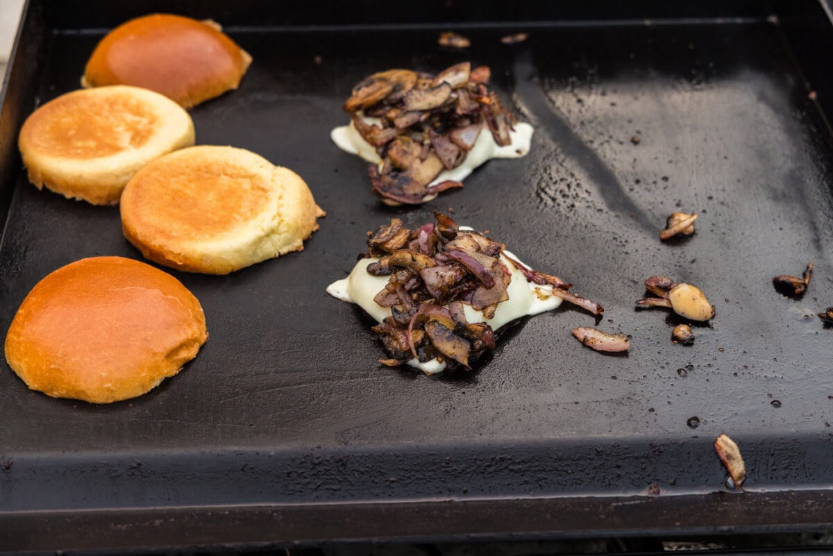 sliced mozzarella on top of portobello mushroom caps with sliced mushrooms on top