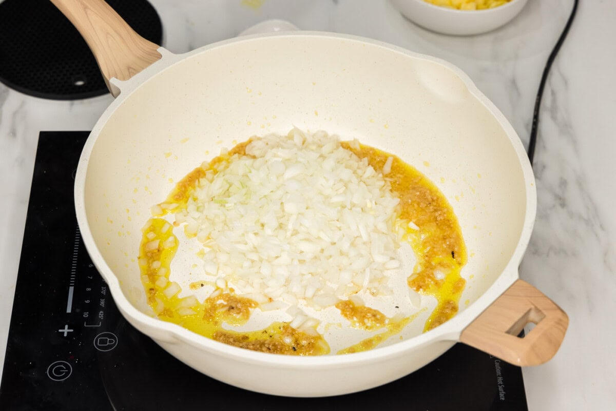 diced onion added to skillet with garlic, ginger, and olive oil