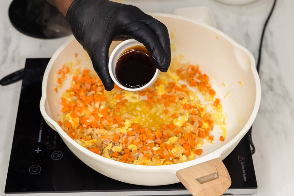 adding oyster sauce to skillet with egg and veggies