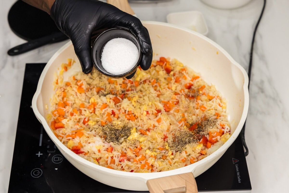 adding salt and sugar to skillet of fried rice