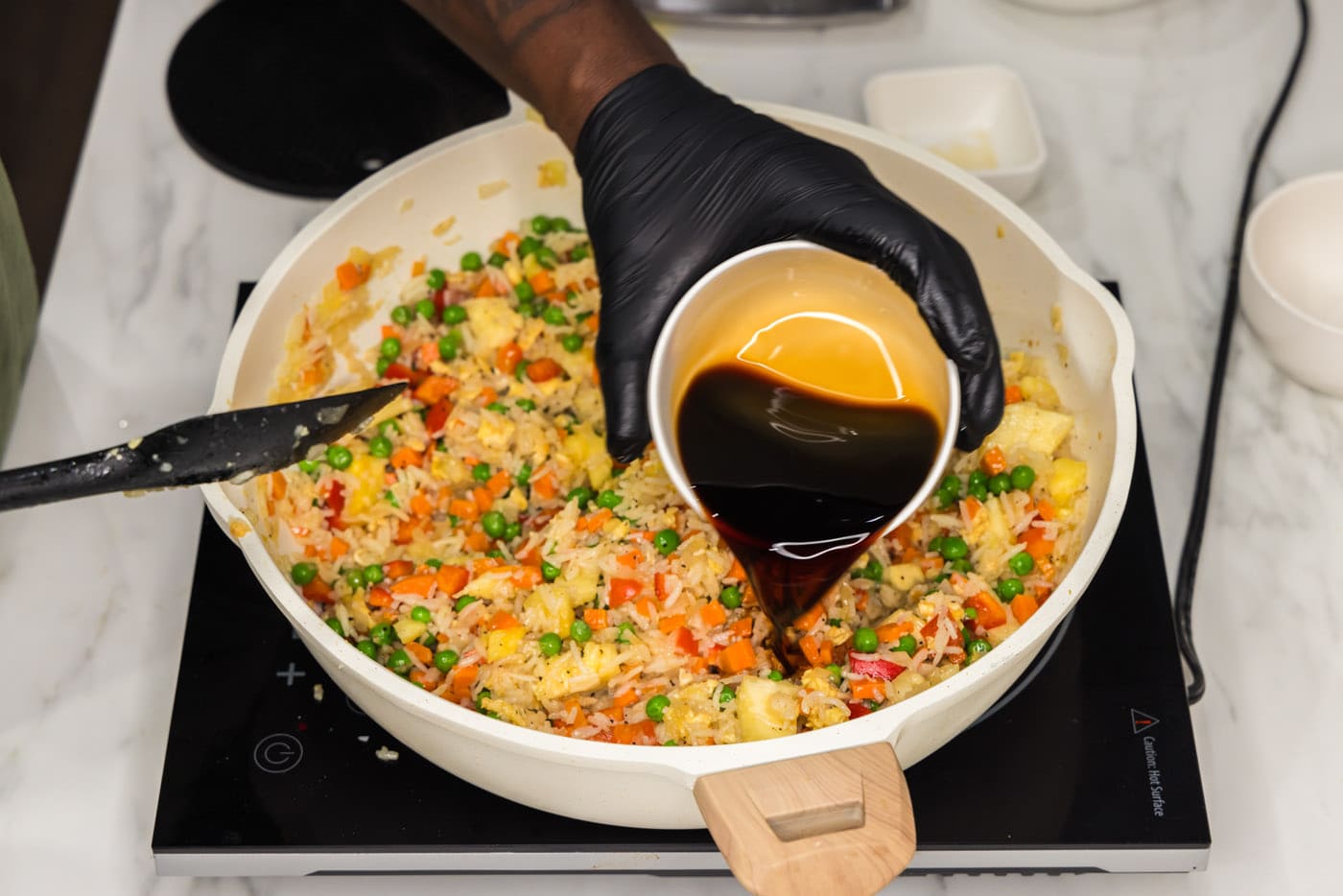 pouring soy sauce into skillet with pineapple fried rice