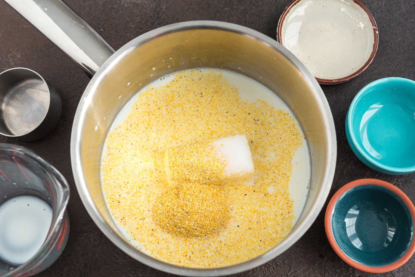 milk, sugar, cornmeal, salt, and butter cooking in a saucepan