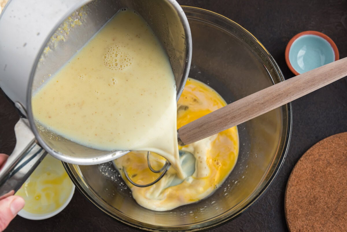 pouring milk mixture into bowl of egg and active yeast