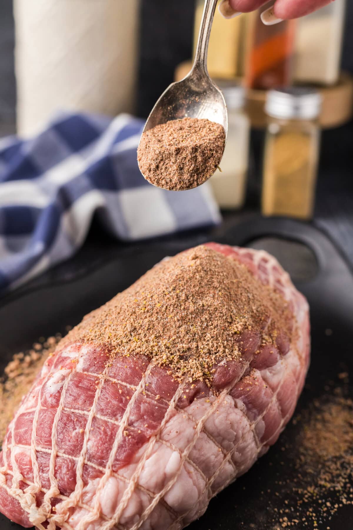 Spoonful of Pulled Pork Rub held above a boneless pork shoulder