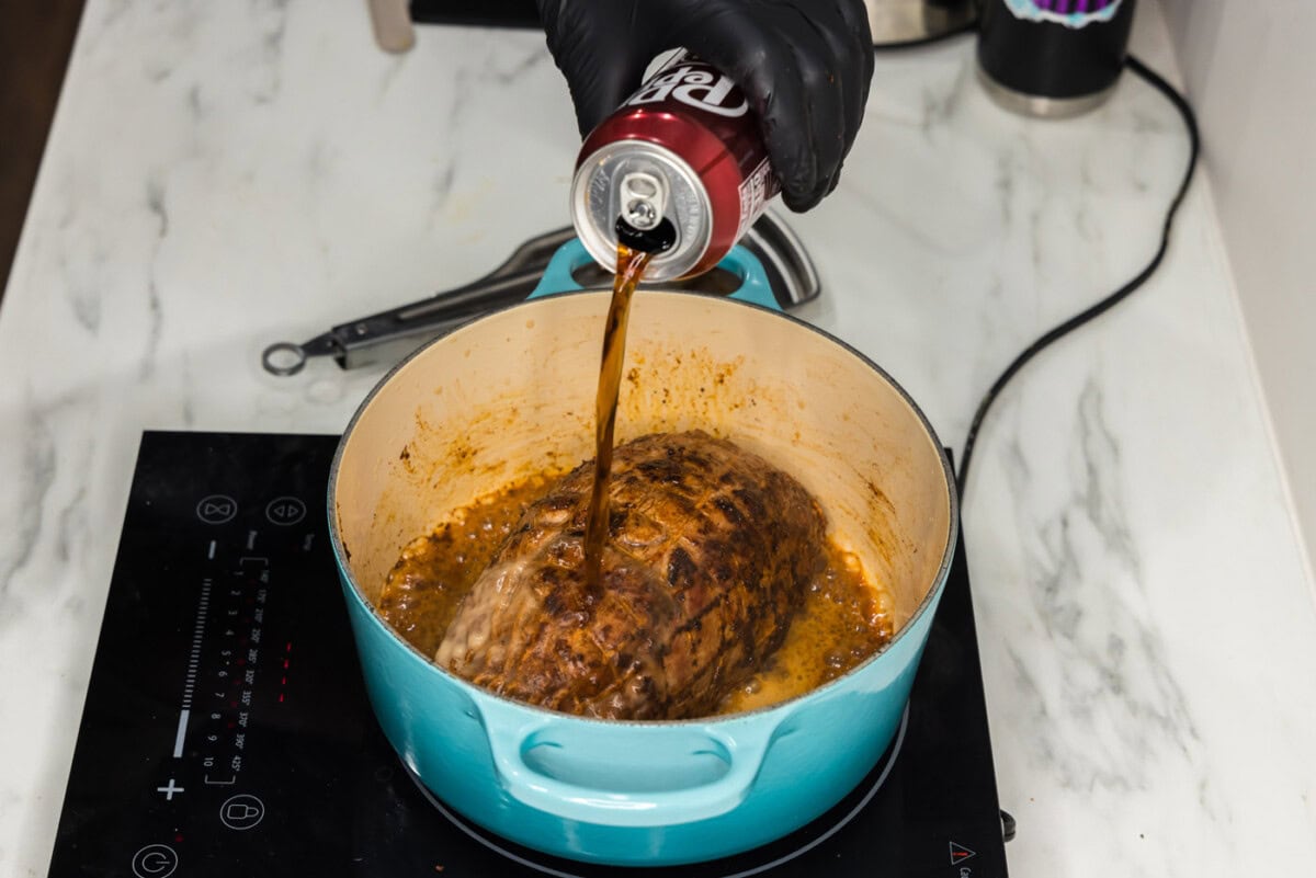 pouring dr pepper on top of pork shoulder