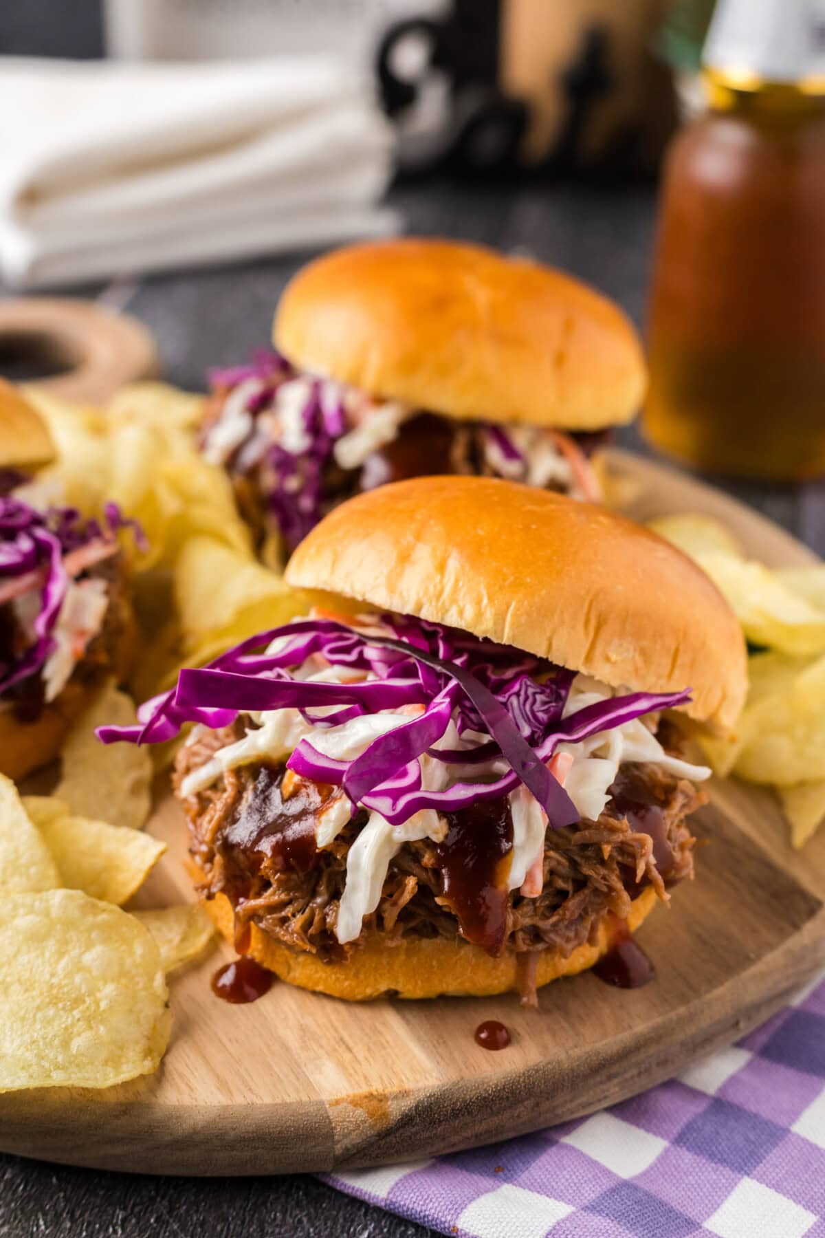Pulled Pork Sandwich on a wooden board with the top bun sliding off