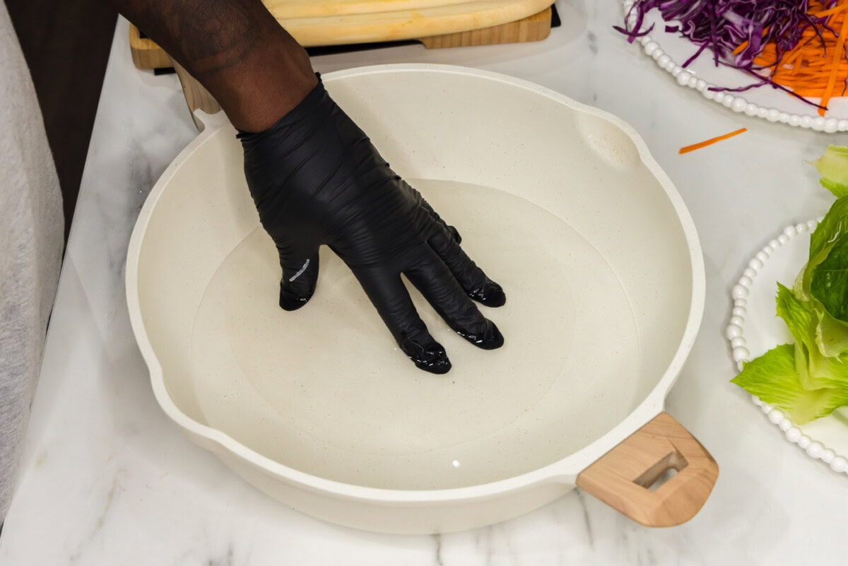spring roll wrapper dipped in a skillet of water