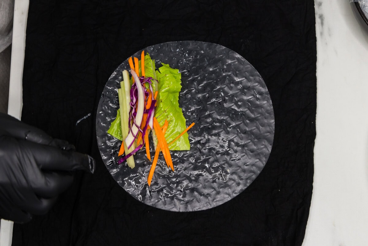 carrots, lettuce, and cabbage added to spring roll wrapper