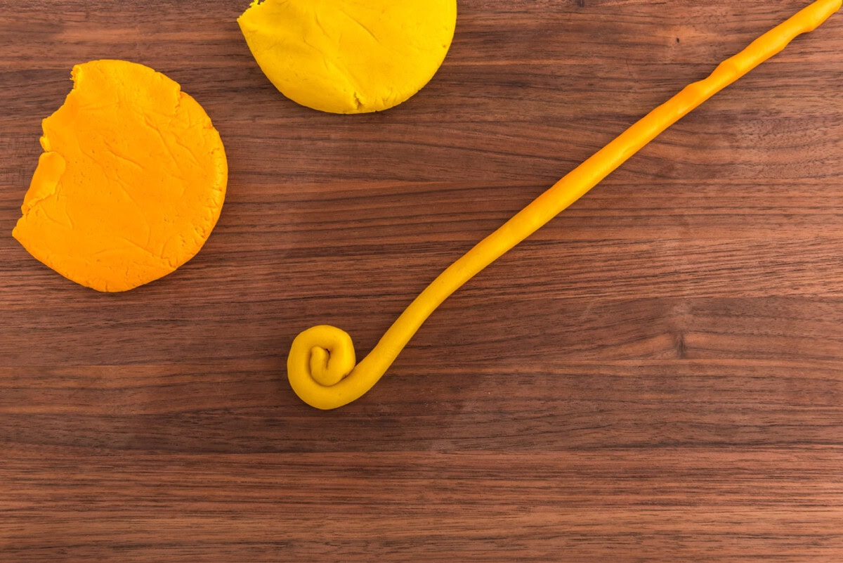 rolling yellow cookie dough into a coil