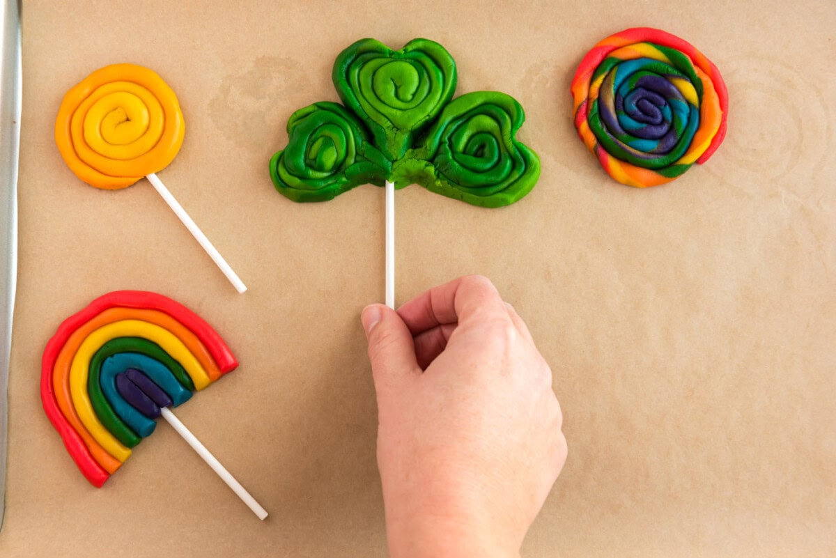 adding lollipop sticks to shamrock cookies