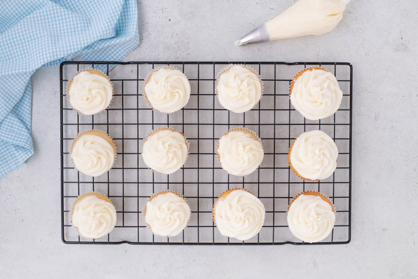 frosted vanilla cupcakes on a wire cooling rack