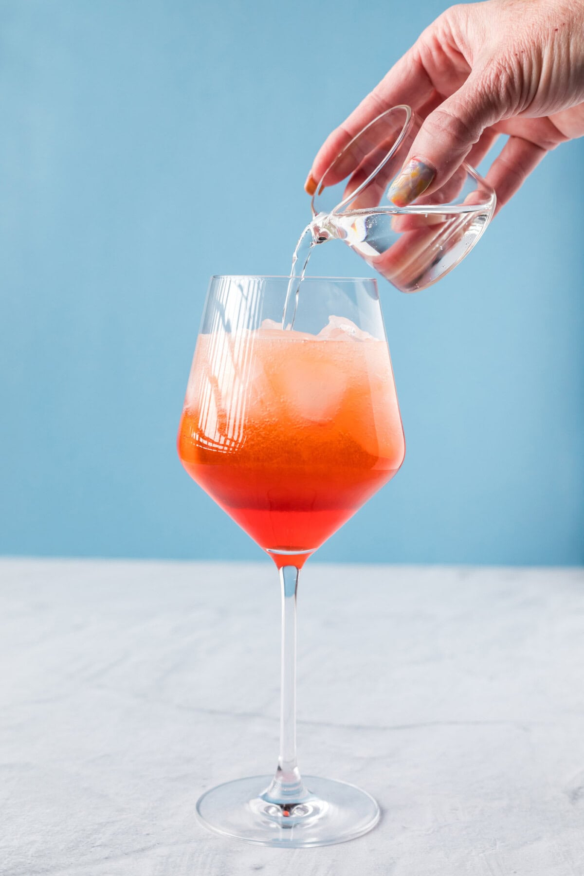 pouring club soda into aperol spritz