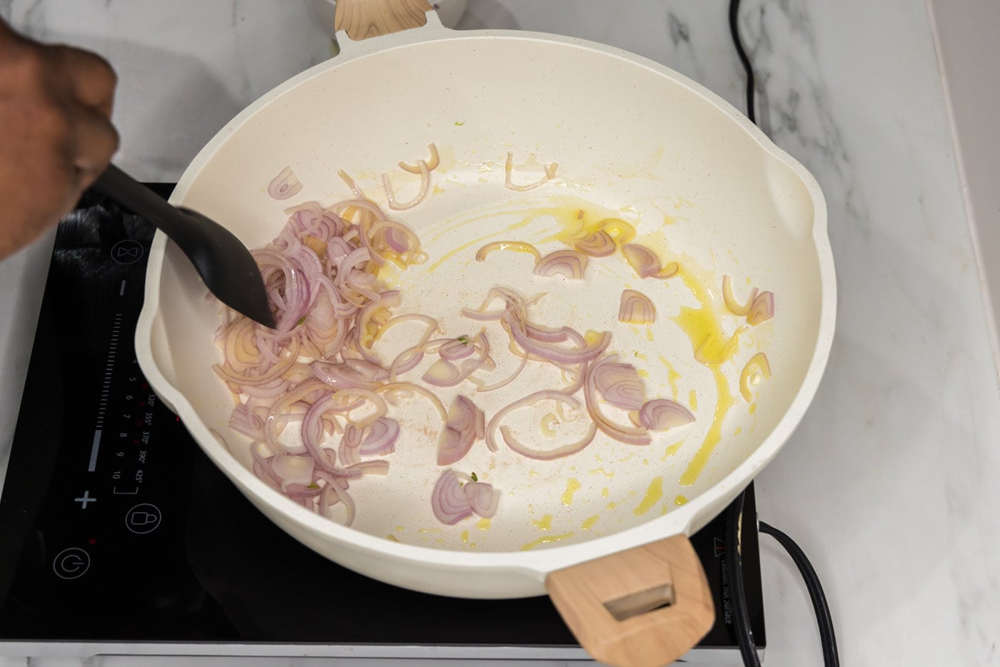 sliced shallots cooking in a pan of olive oil
