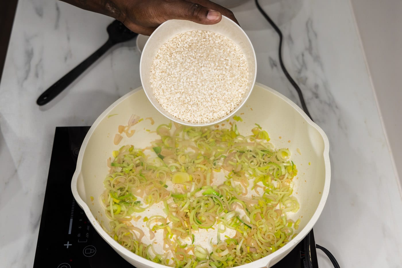 adding arborio rice to skillet with leeks and shallot mixture