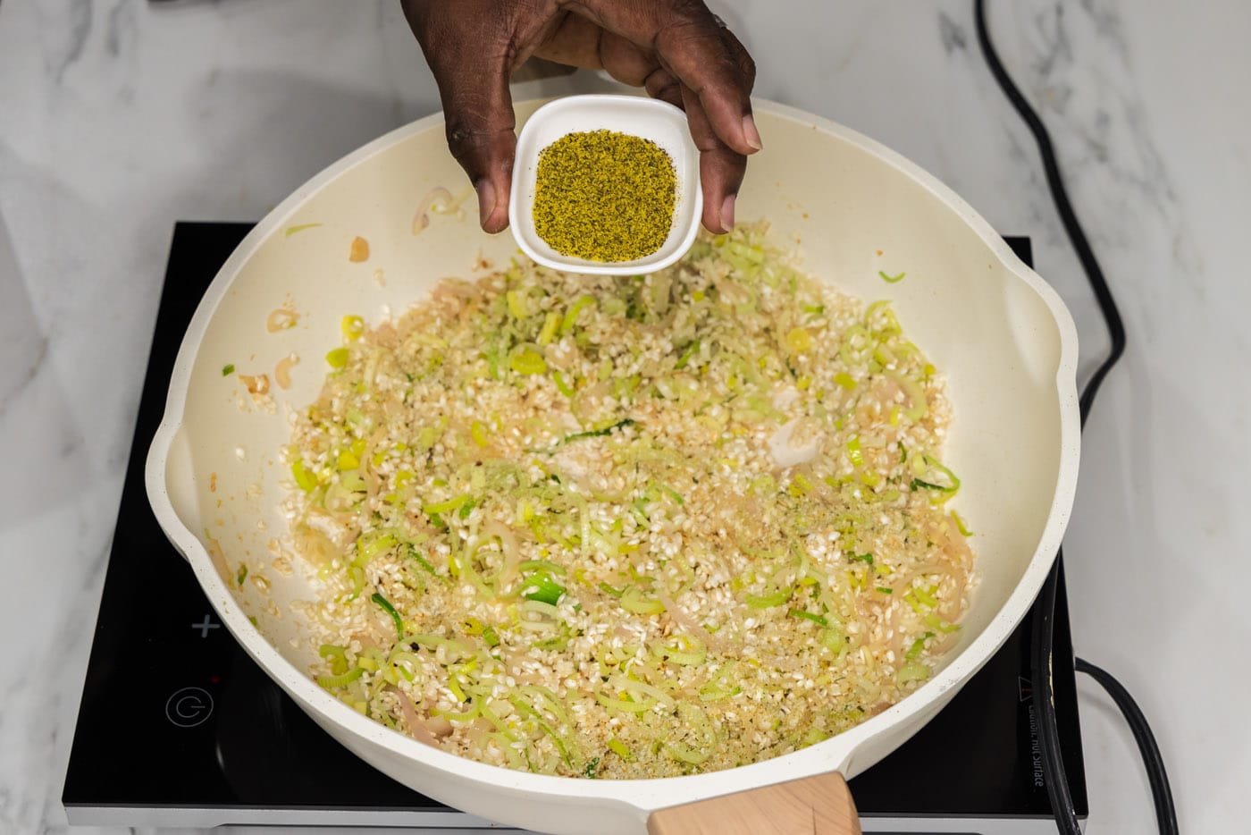 adding lemon pepper to risotto in a skillet