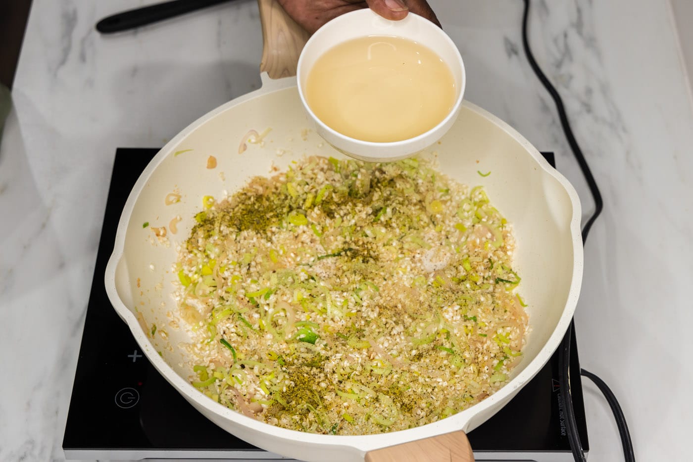 adding white wine to skillet with risotto mixture