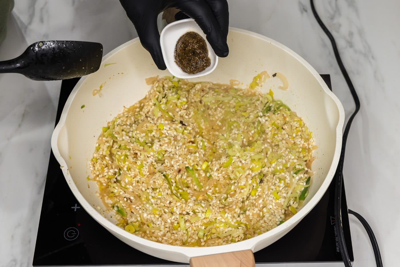 adding bouillon base to skillet with risotto