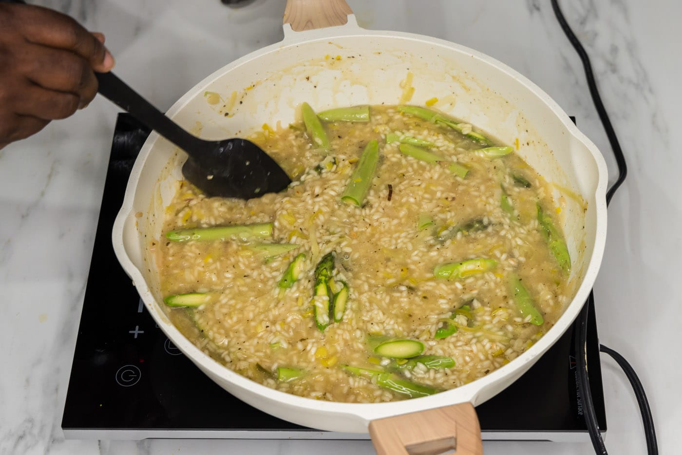 turning asparagus spears in a skillet with creamy risotto
