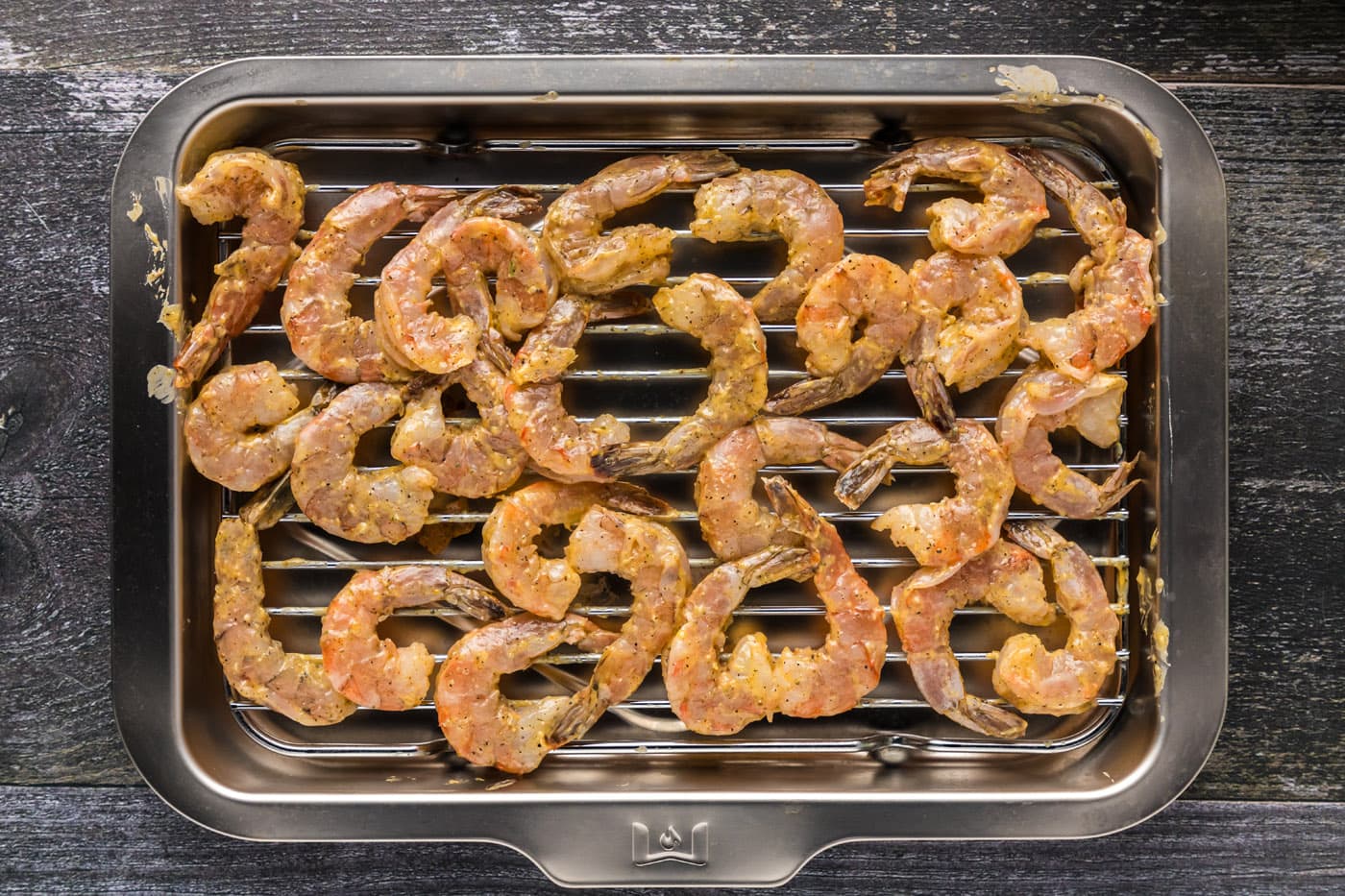 buttered seasoned shrimp on a wire cooling rack over a baking sheet