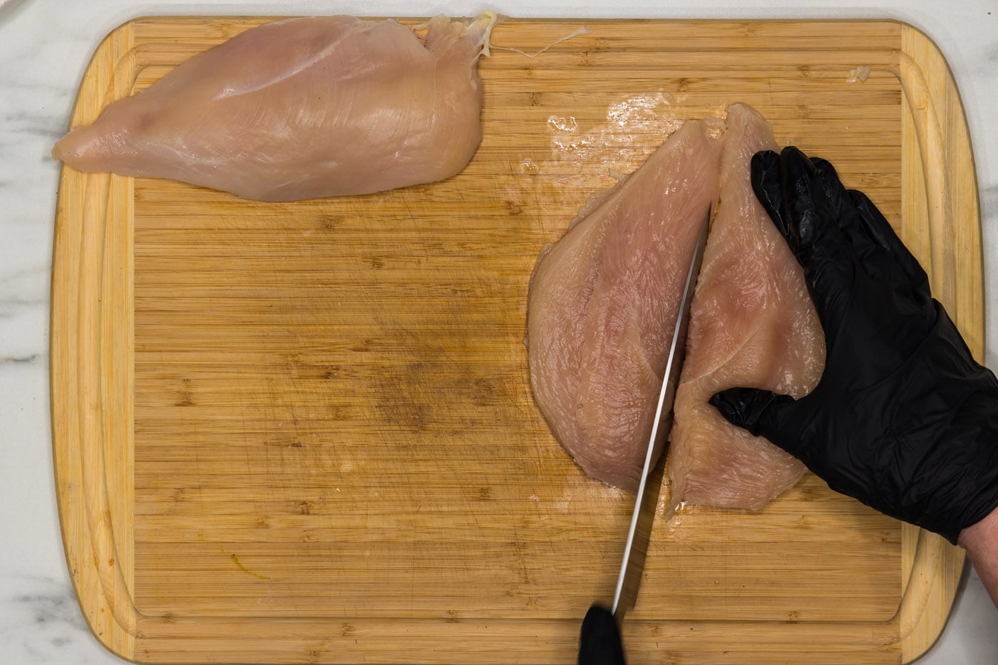 slicing chicken in half lengthwise with a knife
