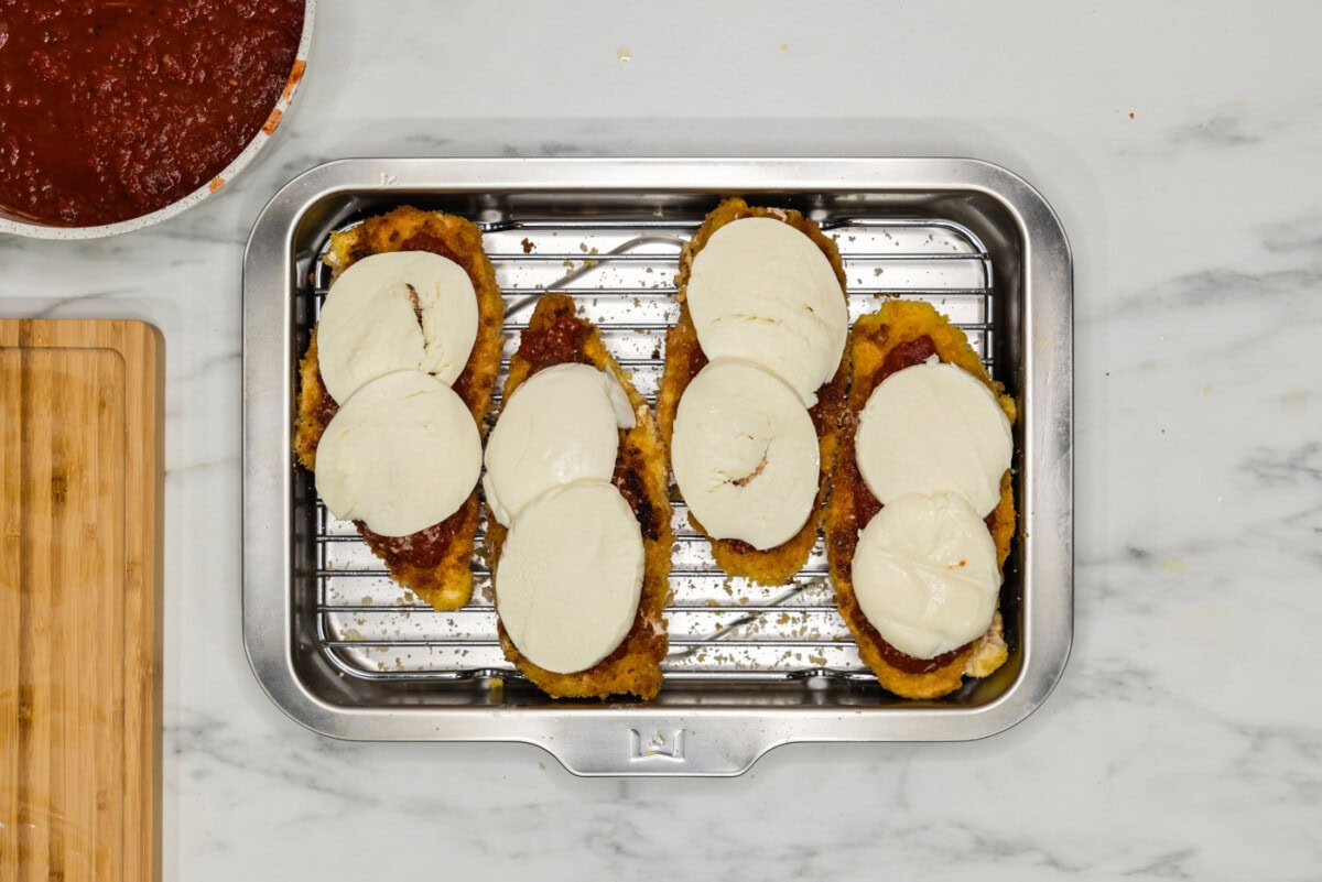 sliced mozzarella cheese on top of marinara coated chicken