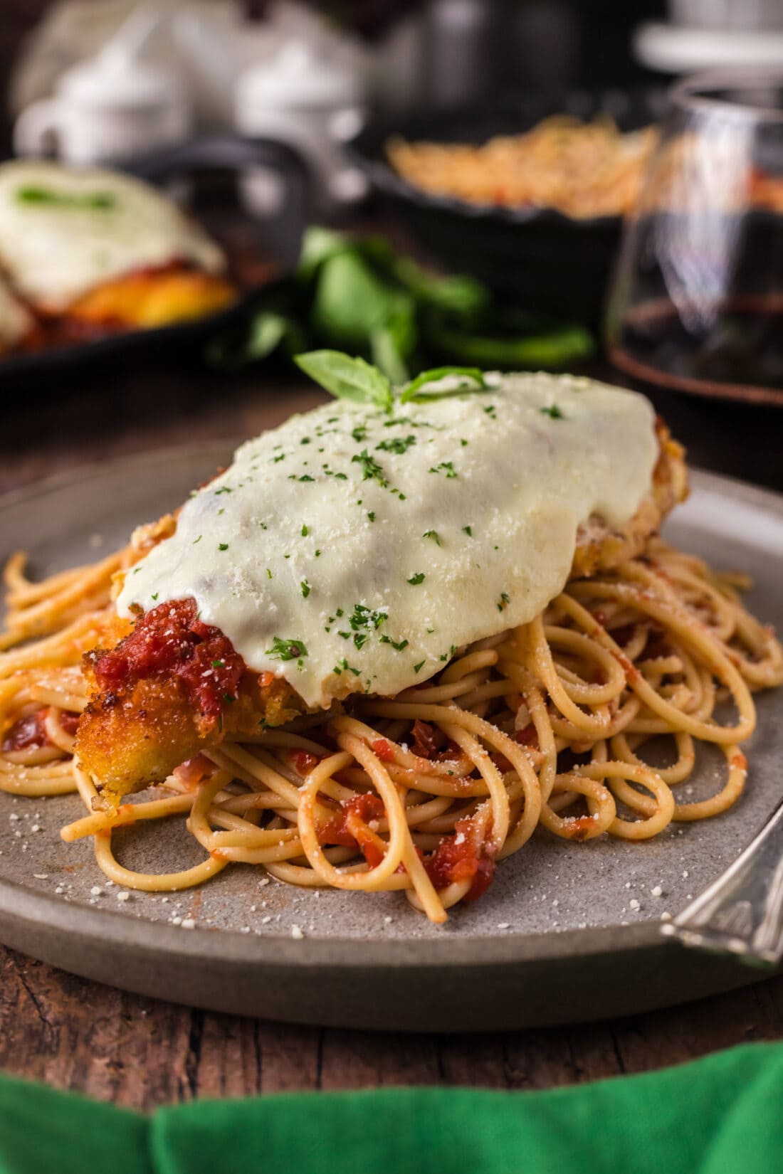 Chicken Parmesan served over spaghetti on a plate