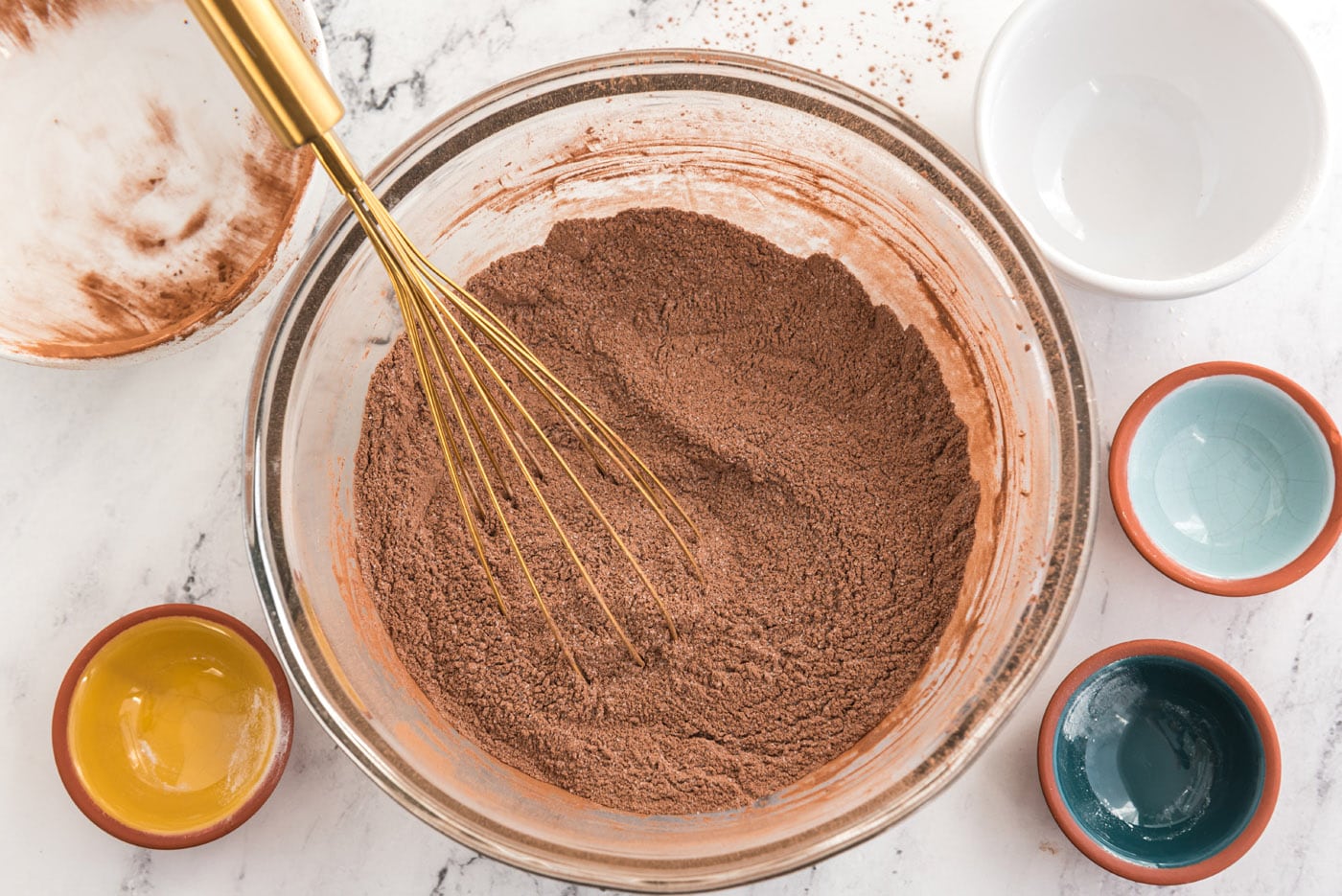 whisking sugar, flour, cocoa powder, baking soda, baking powder, and salt in a bowl.