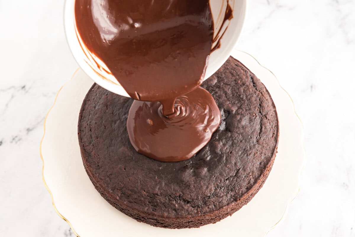 pouring ganache over chocolate cake