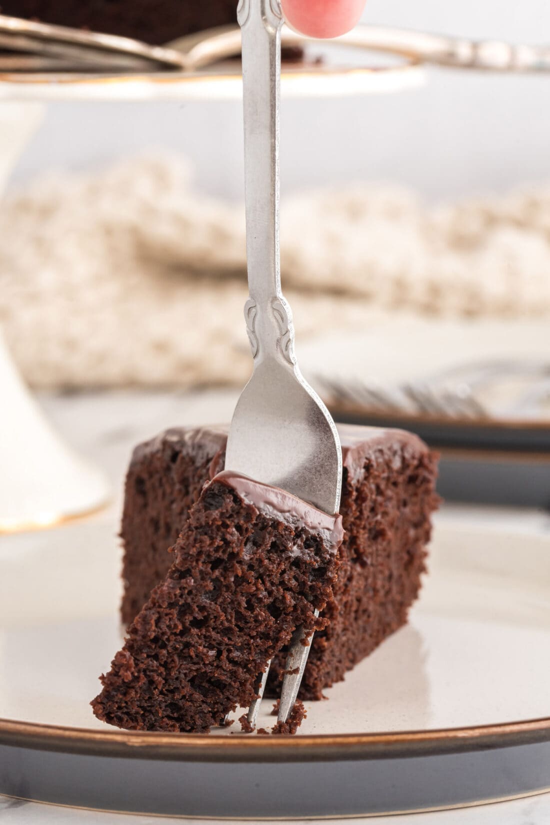Fork taking a piece of Dark Chocolate Cake from a slice on a plate