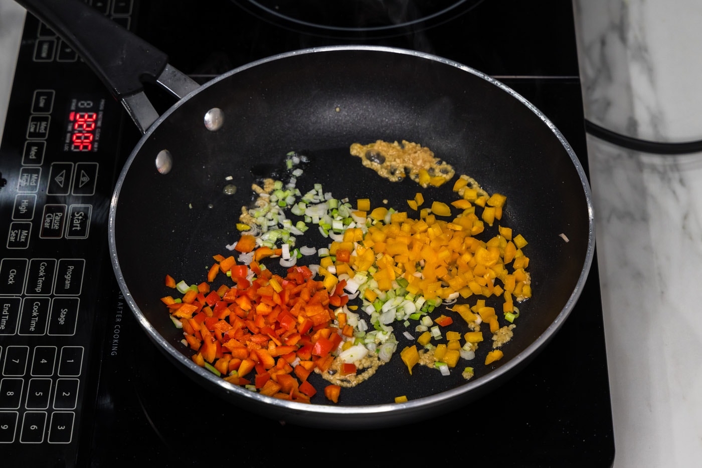 peppers, garlic, and green onions in a skillet