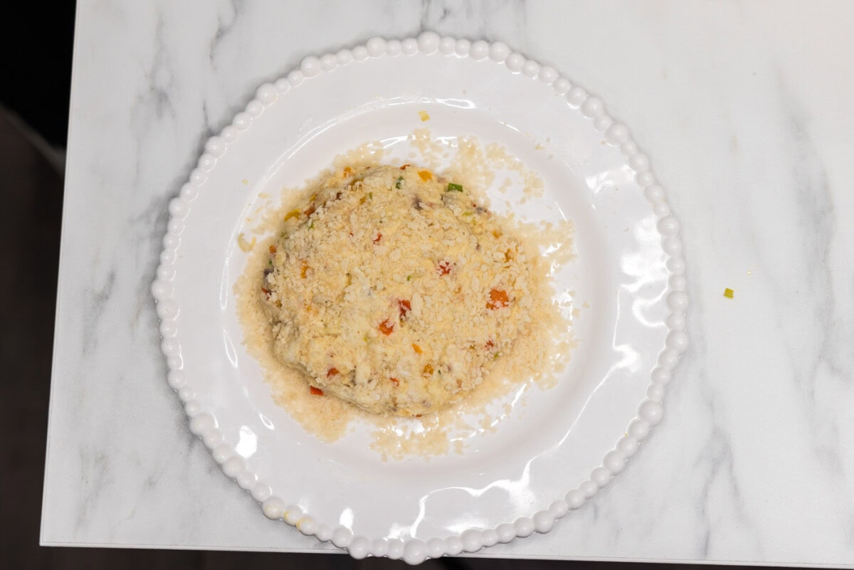 fish patty on top of breadcrumbs on a plate
