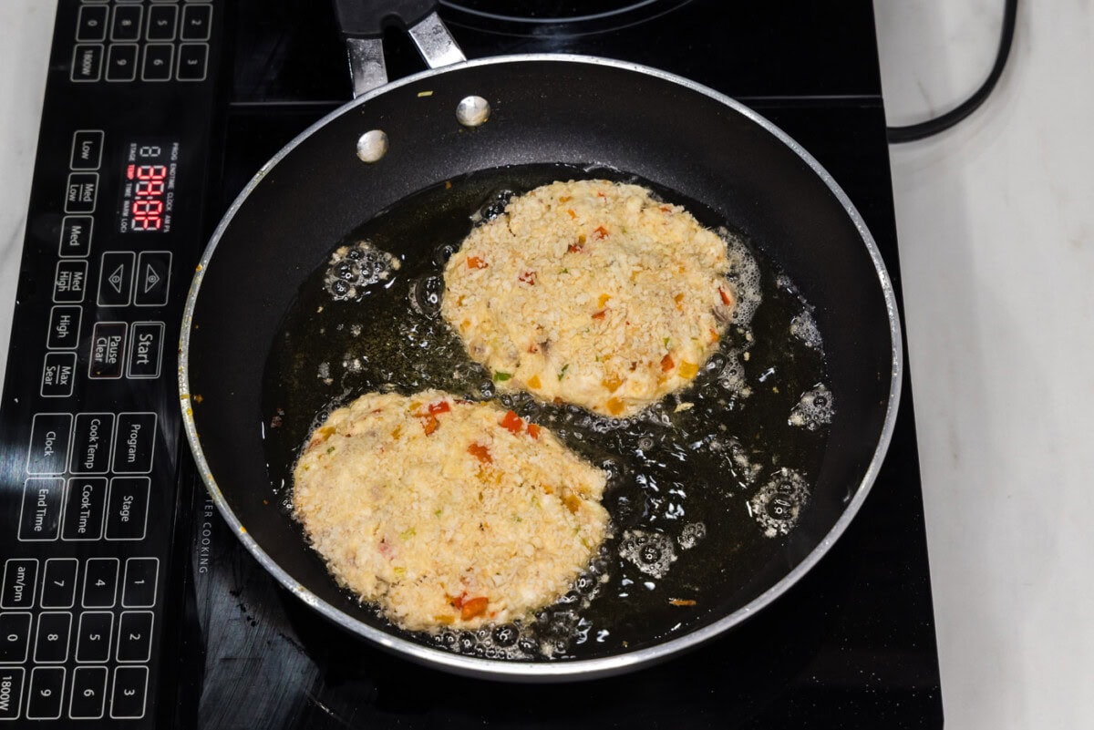 frying fish cakes in a skillet of oil