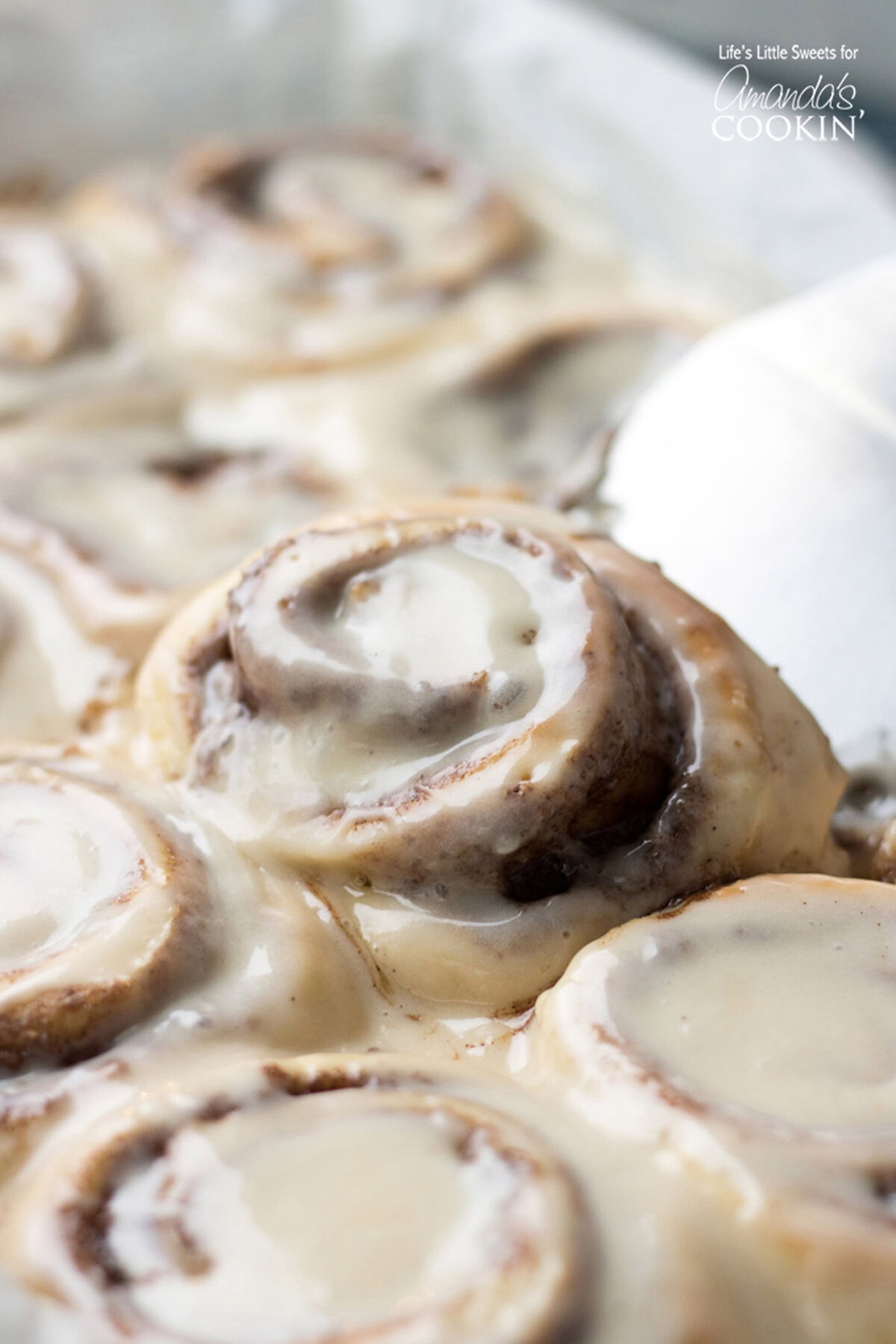 These Homemade Cinnamon Rolls are a true classic. Topped with cream cheese frosting, these gooey cinnamon rolls satisfy your sweet craving! They also make the perfect holiday morning breakfast with the family. #breakfast #cinnamonrolls #breadrecipes #holidaybreakfast #dough #cinnamon Homemade Cinnamon Roll being lifted out of the pan