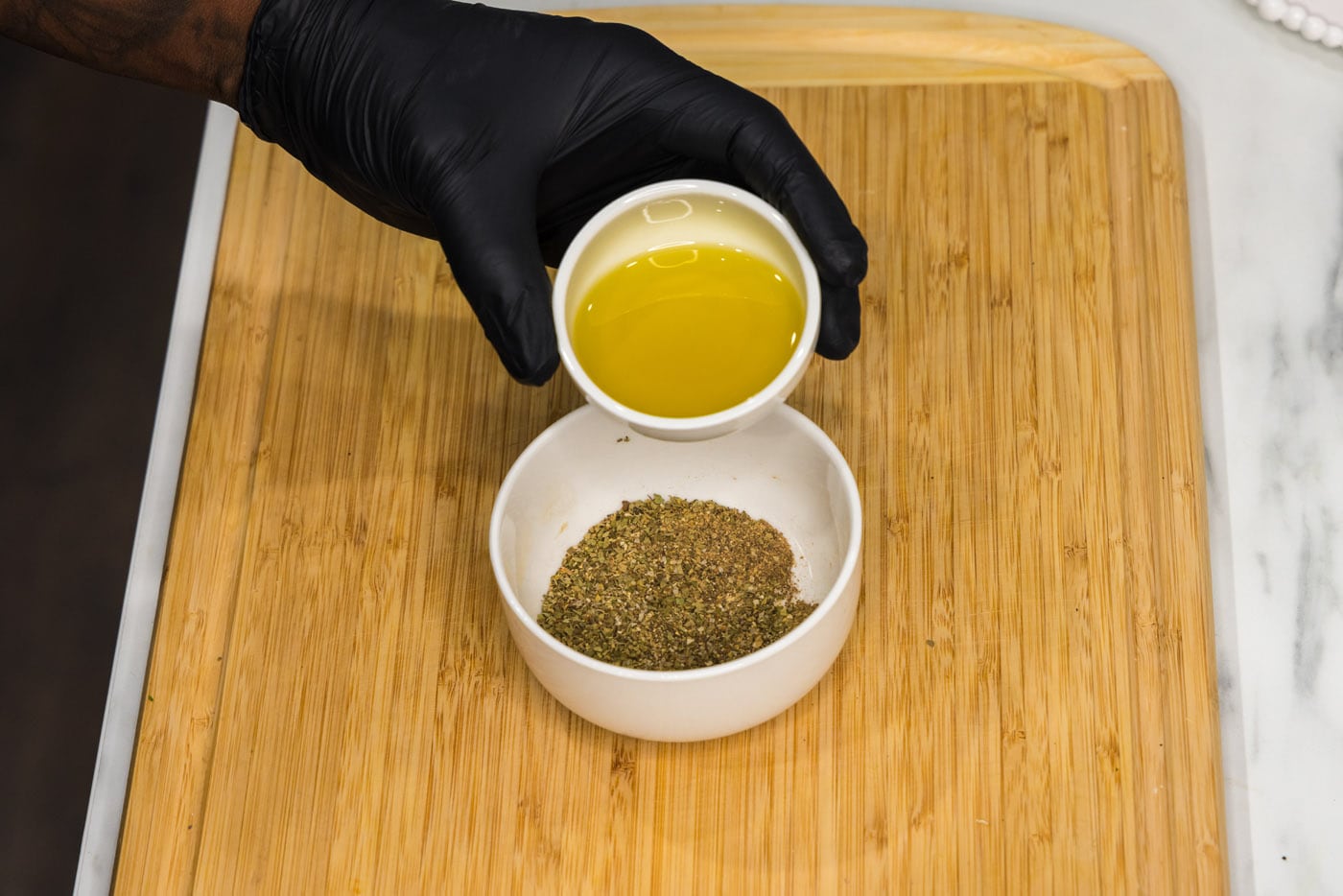 adding olive oil to seasonings in a bowl