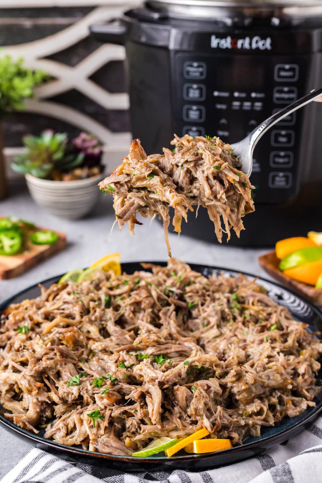 Forkful of Instant Pot Carnitas held above a plate of Instant Pot Carnitas