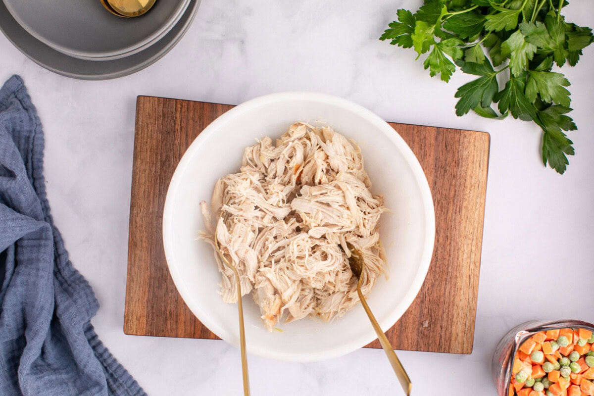 shredding chicken breasts with two forks in a bowl