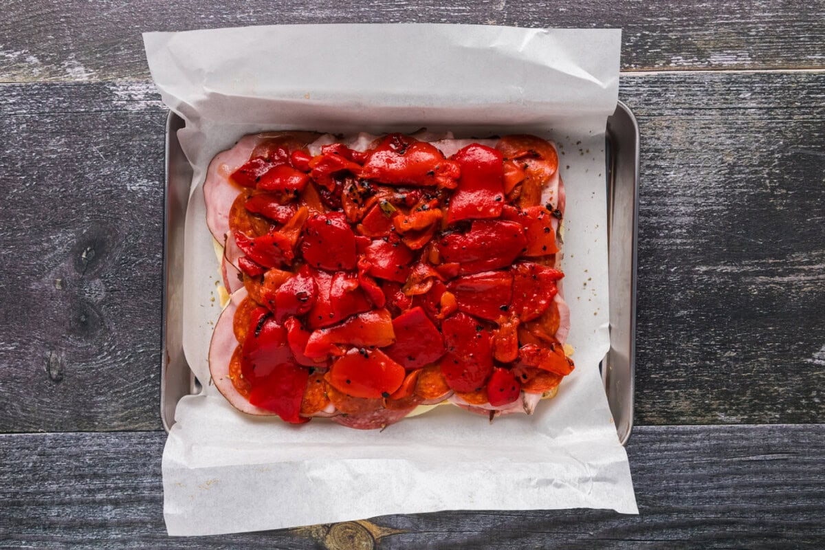 roasted bell peppers on top of salami, ham, and pepperoni