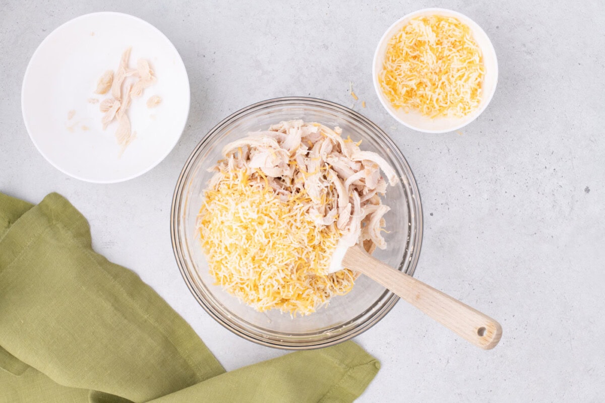adding shredded chicken and cheese to mexican pinwheel filling