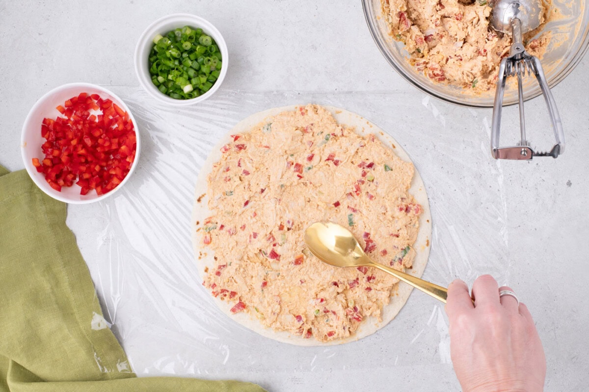 spreading cream cheese taco filling over a burrito tortilla shell