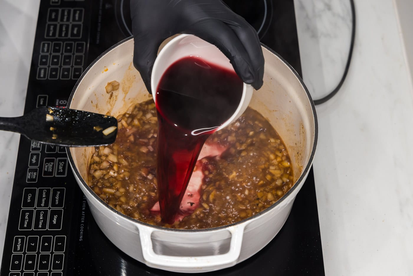 pouring red wine into braising liquid