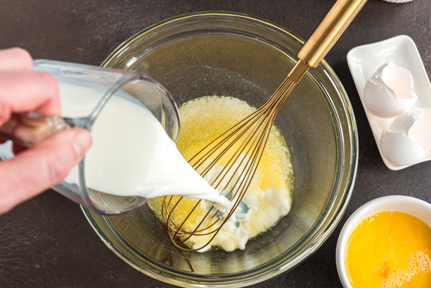 pouring milk into bowl of melted butter