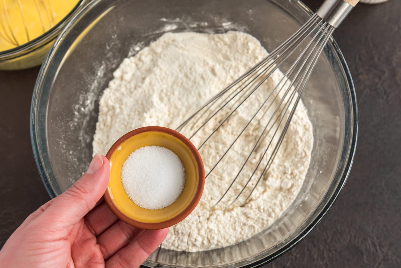 adding salt to flour in a bowl with a whisk