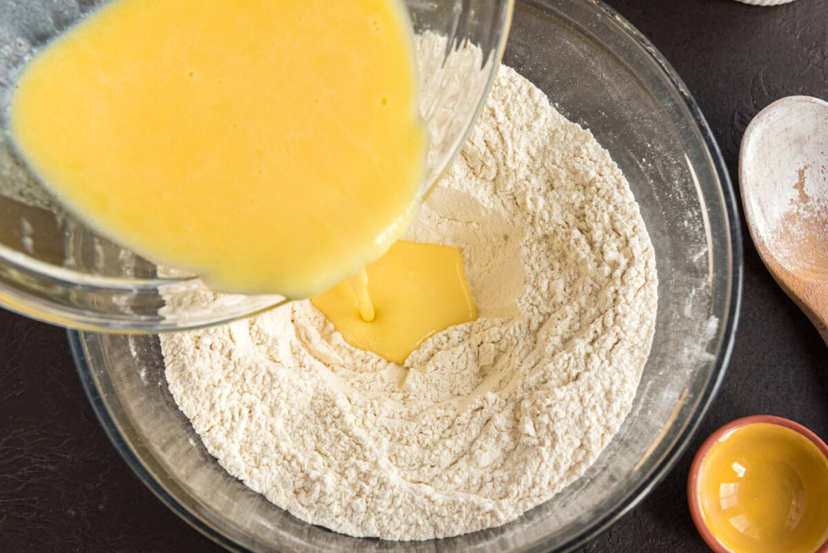 pouring melted butter and egg mixture into well of flour
