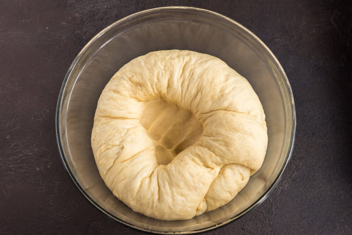 punching a hole into yeast dough in a bowl