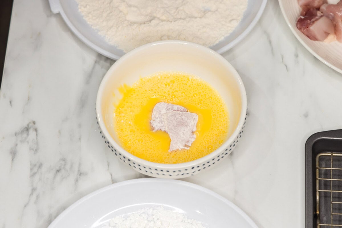 coating flour dredged chicken pieces in egg