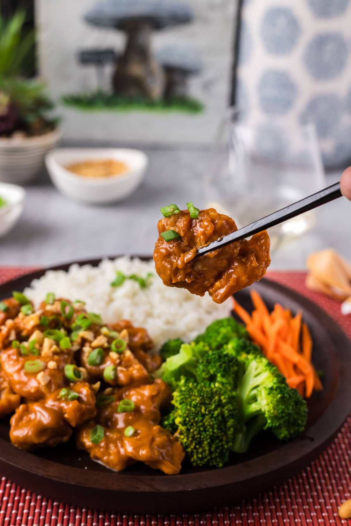 Chopsticks holding up a piece of Peanut Butter Chicken