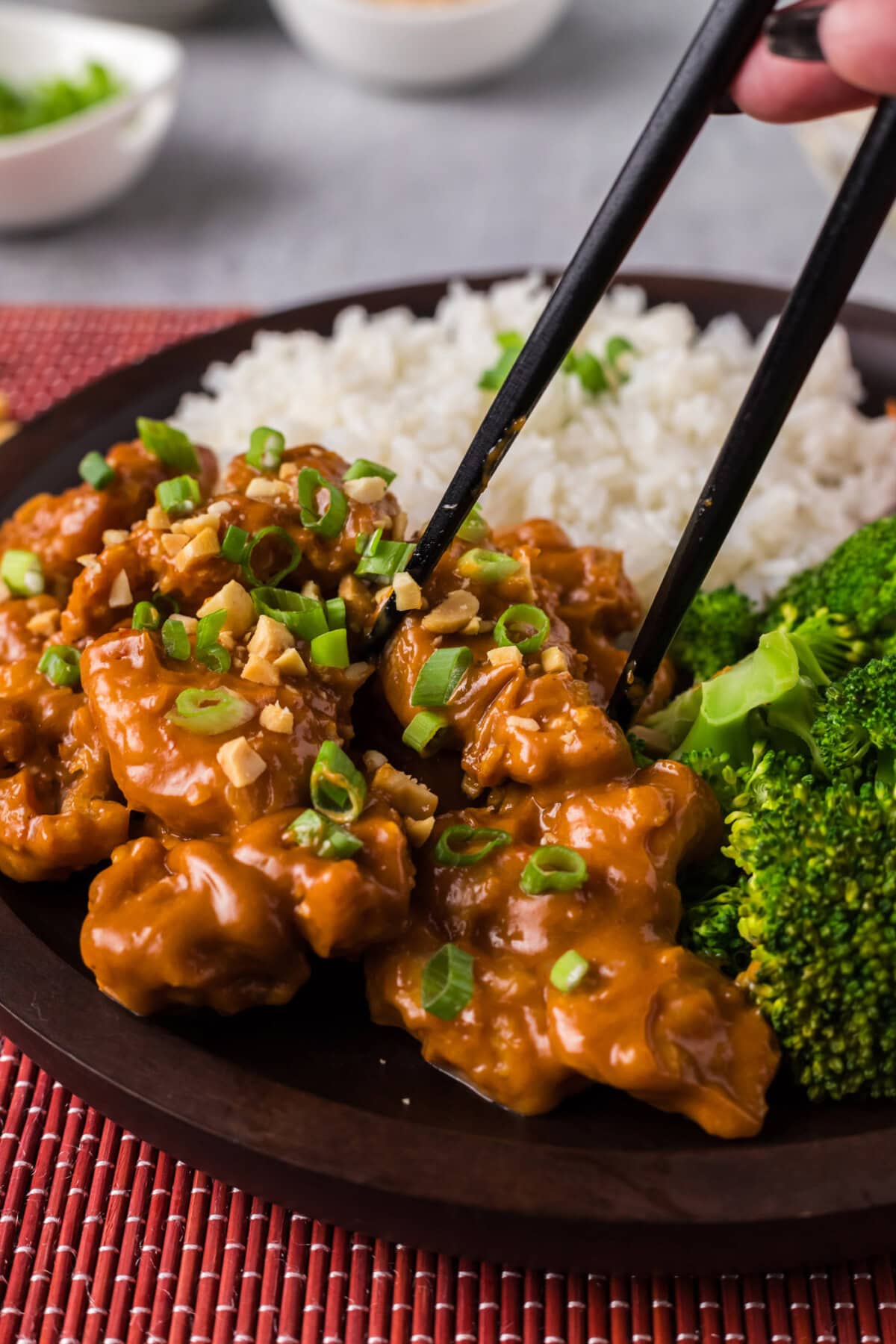 Chopsticks picking up a piece of Peanut Butter Chicken