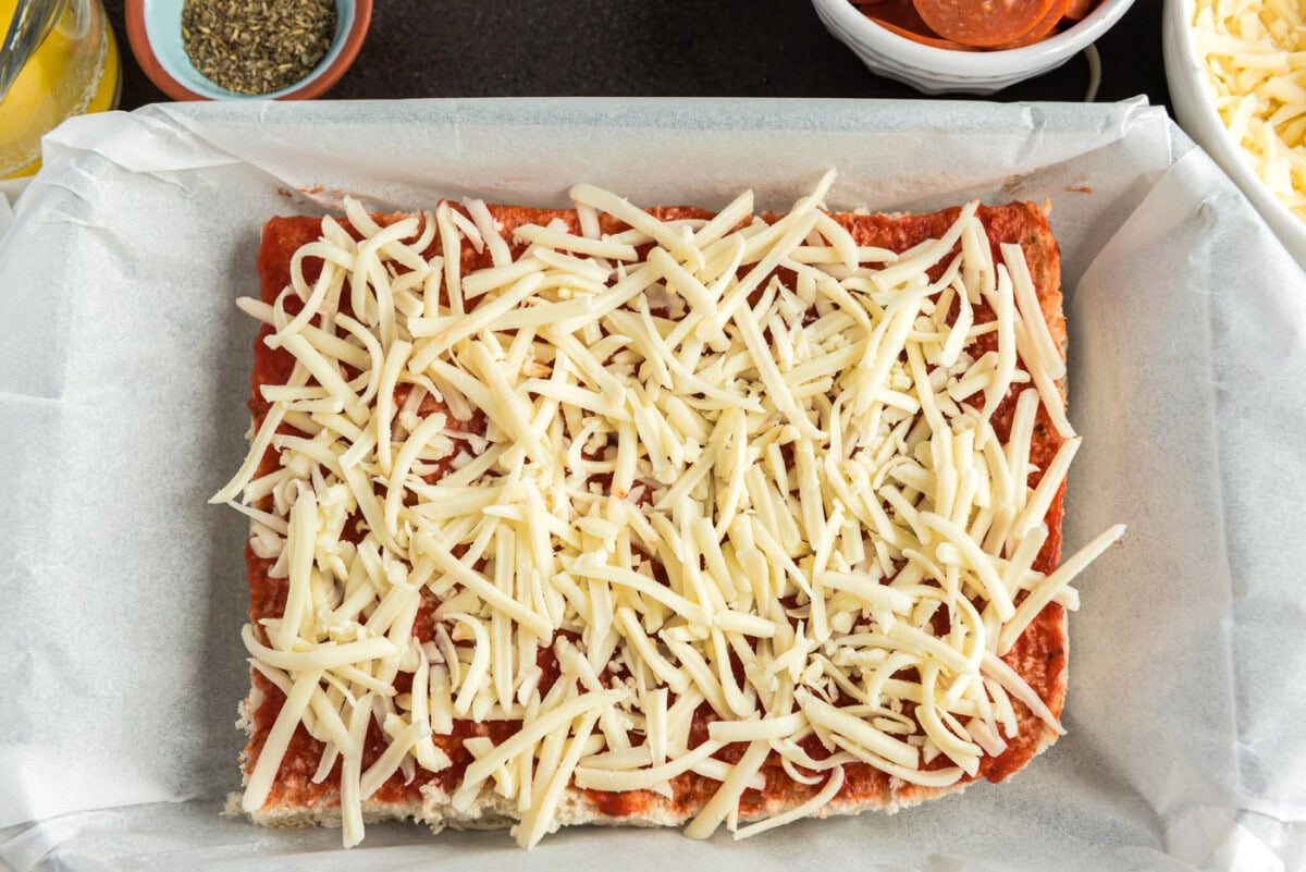 shredded mozzarella cheese on top of pizza sauce