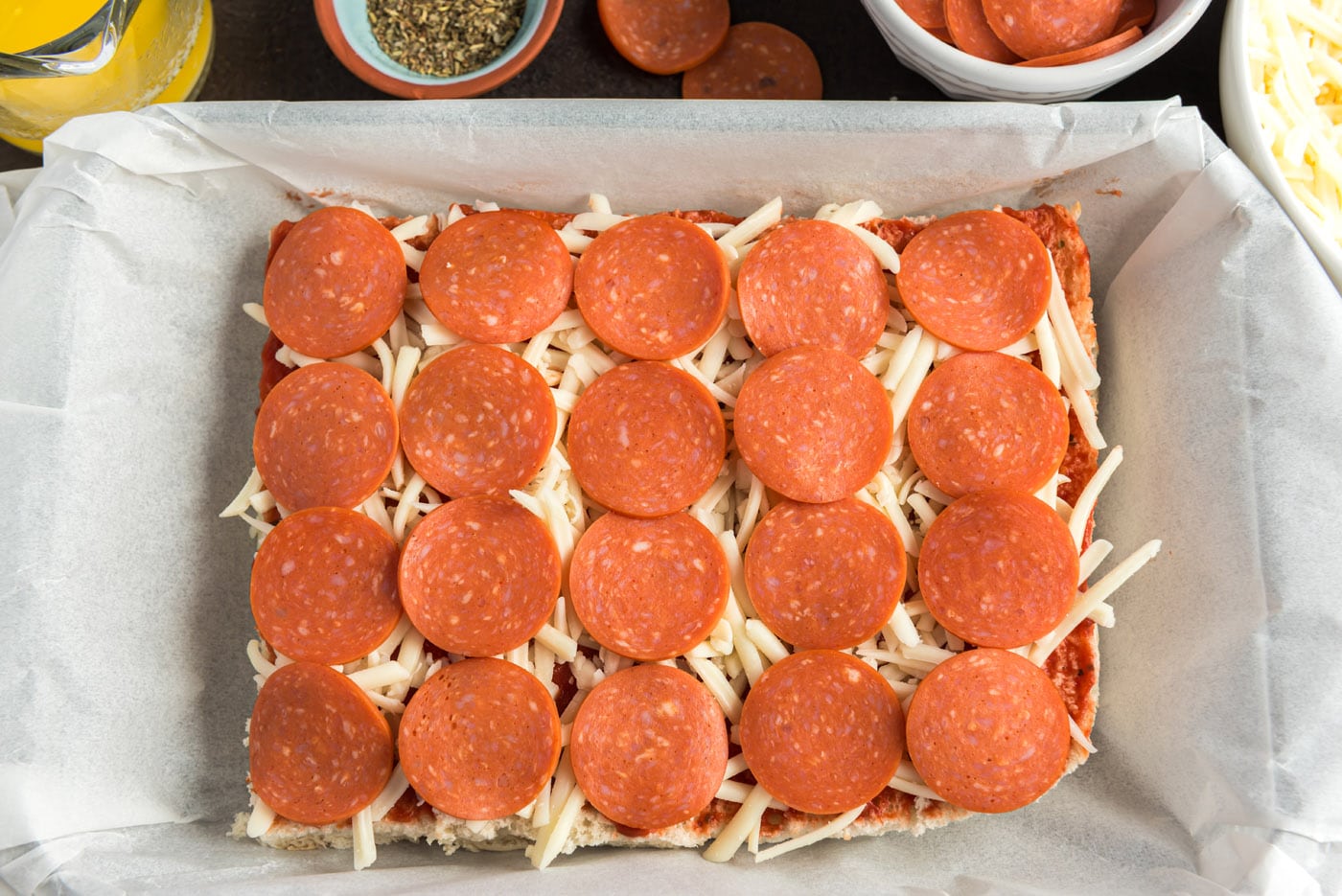 pepperoni slices on top of mozzarella and pizza sauce